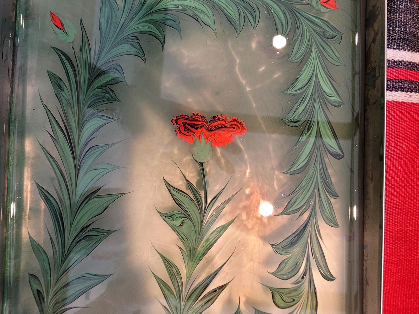 Ebru art in progress — red rose and flower pattern forming in water tray