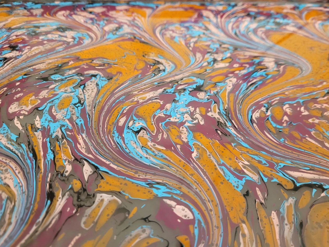 Colorful ebru swirl pattern with warm yellow, orange and blue hues