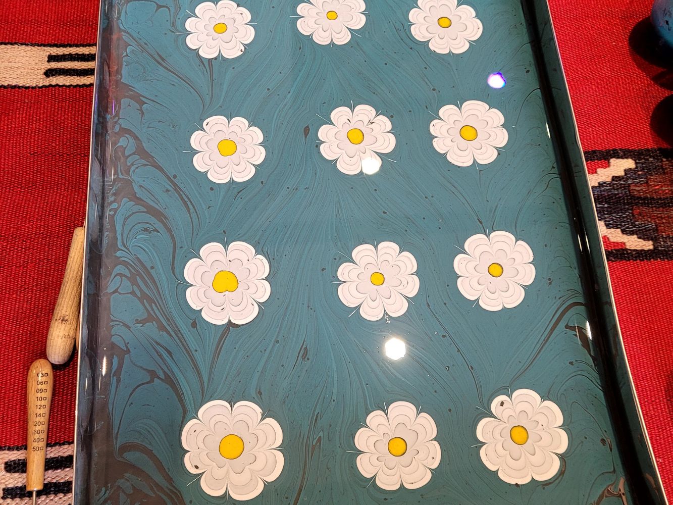 Ebru marbled paper with white daisy flowers on a teal-blue background