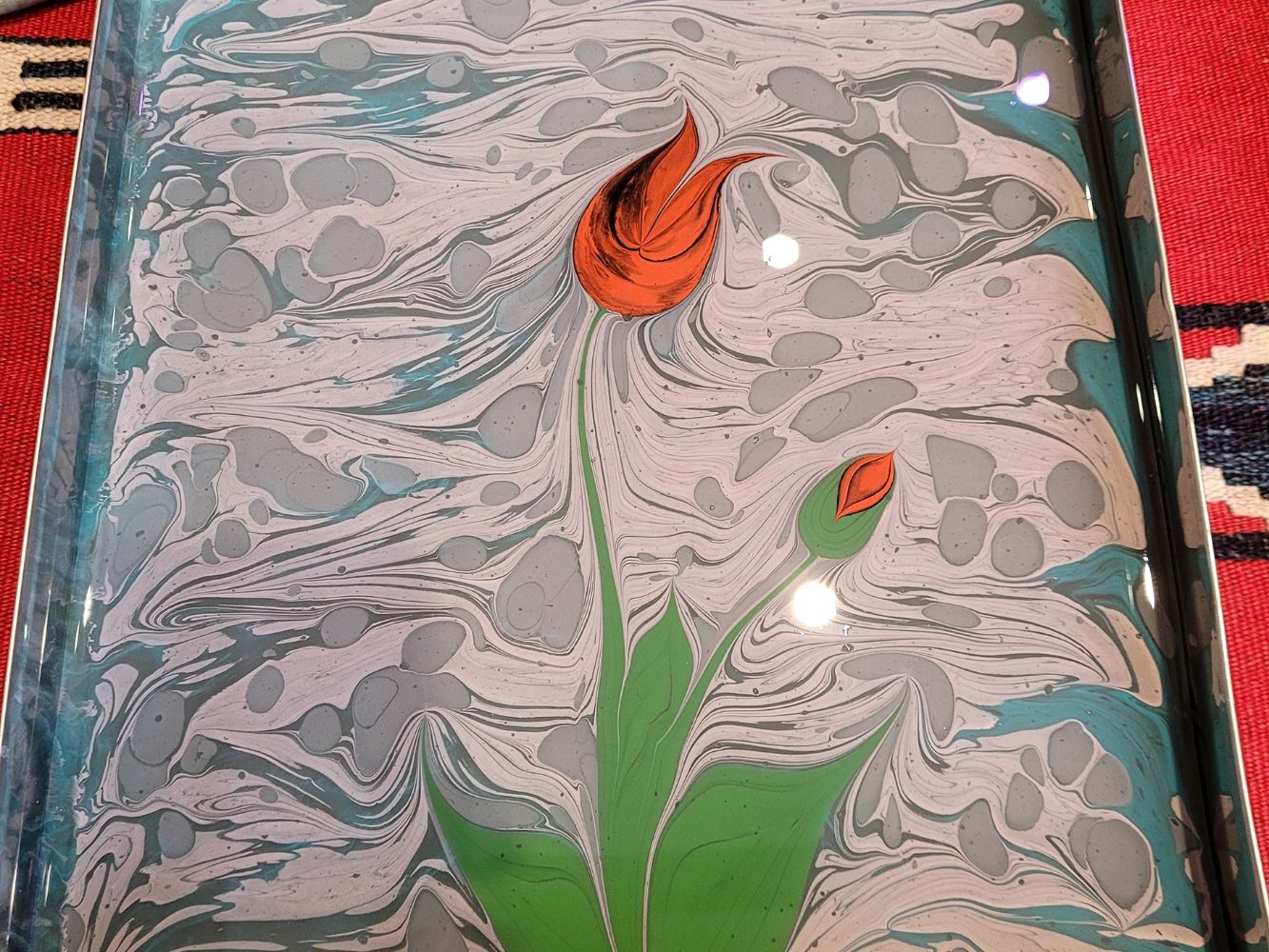 Ebru marbled paper with an orange tulip design and flowing gray marble texture